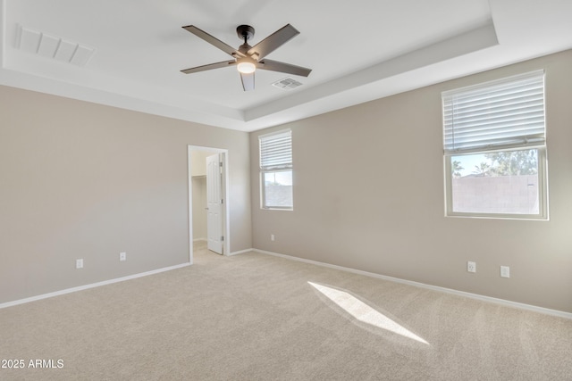 unfurnished room featuring ceiling fan, light colored carpet, and a tray ceiling