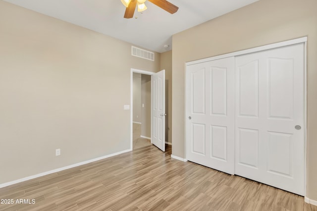 unfurnished bedroom featuring ceiling fan, light hardwood / wood-style floors, and a closet