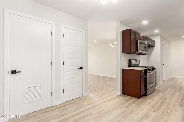 kitchen with appliances with stainless steel finishes, light wood-type flooring, light countertops, and dark brown cabinetry