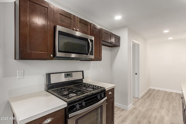 kitchen featuring light wood finished floors, dark brown cabinets, appliances with stainless steel finishes, and light countertops