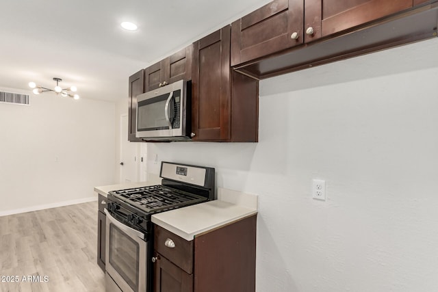 kitchen featuring dark brown cabinets, appliances with stainless steel finishes, light countertops, and visible vents