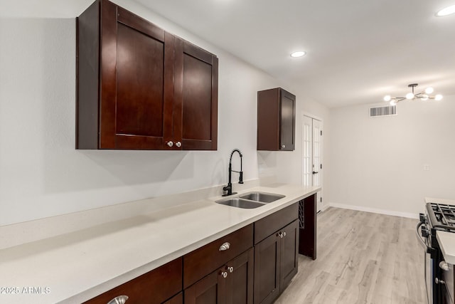 kitchen featuring stainless steel gas range oven, visible vents, light countertops, light wood-type flooring, and a sink