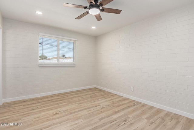 spare room featuring baseboards, brick wall, recessed lighting, and light wood-style floors