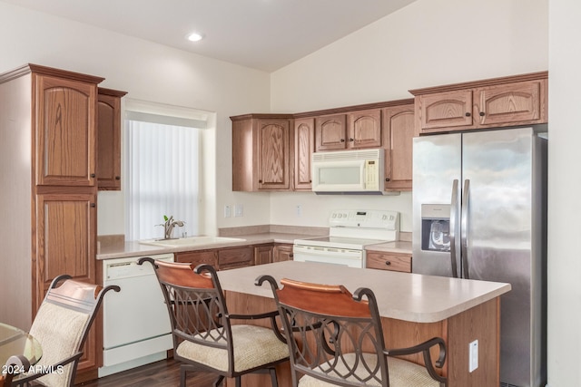 kitchen with sink, white appliances, a kitchen breakfast bar, dark hardwood / wood-style floors, and vaulted ceiling