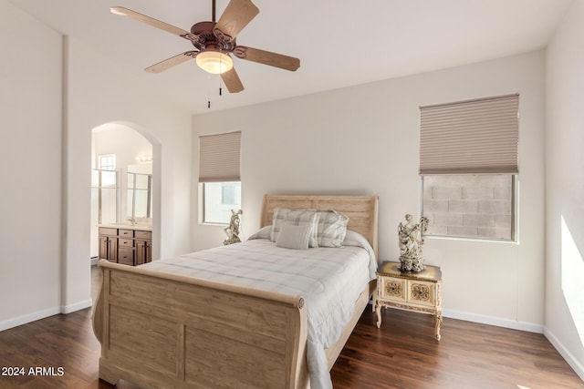 bedroom featuring ceiling fan, sink, ensuite bath, and dark wood-type flooring