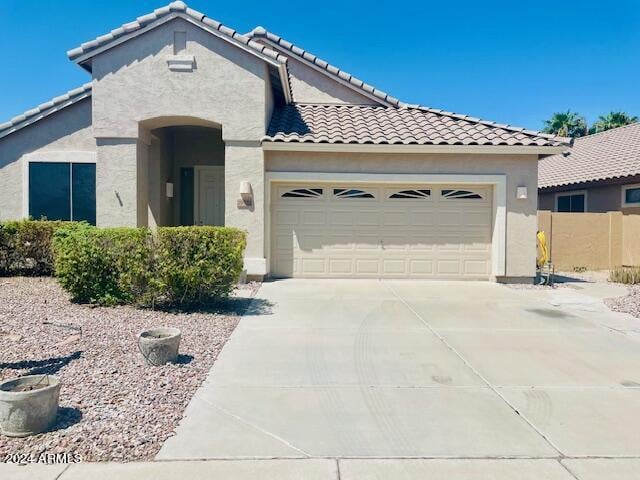 mediterranean / spanish-style house featuring a tile roof, stucco siding, driveway, and an attached garage