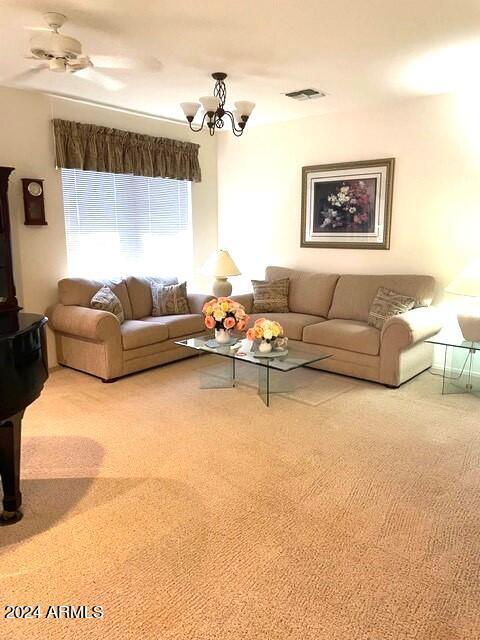 unfurnished living room featuring carpet flooring, ceiling fan with notable chandelier, and visible vents