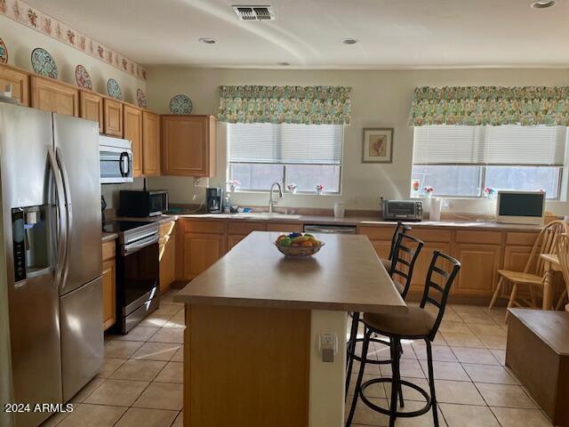 kitchen with light tile patterned floors, visible vents, appliances with stainless steel finishes, and a breakfast bar area