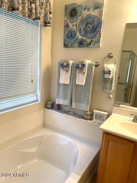 bathroom with a shower stall, a bath, and vanity