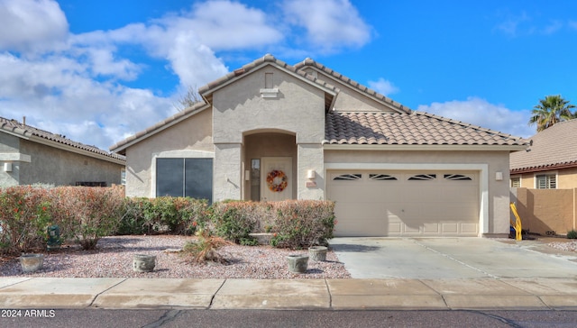 mediterranean / spanish home with concrete driveway, an attached garage, a tile roof, and stucco siding