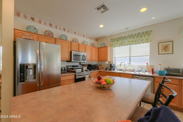 kitchen featuring appliances with stainless steel finishes, light tile patterned floors, and sink