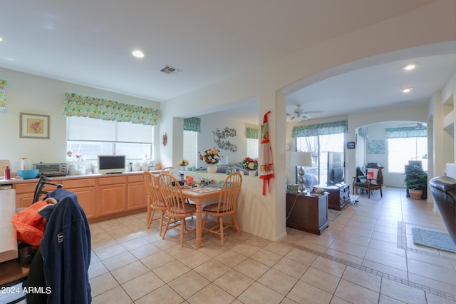 kitchen featuring light tile patterned floors, visible vents, arched walkways, and light brown cabinets