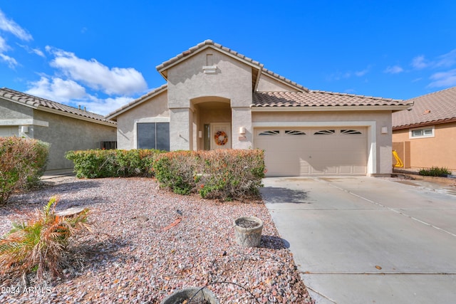 mediterranean / spanish-style home featuring stucco siding, a tiled roof, concrete driveway, and a garage