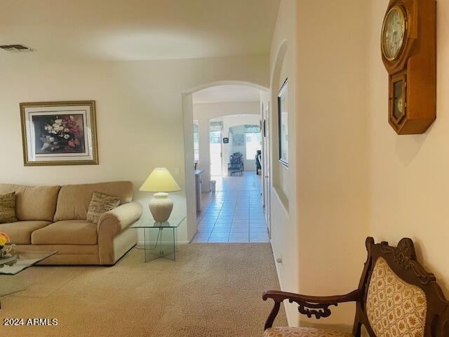 carpeted living area with visible vents, arched walkways, and tile patterned flooring