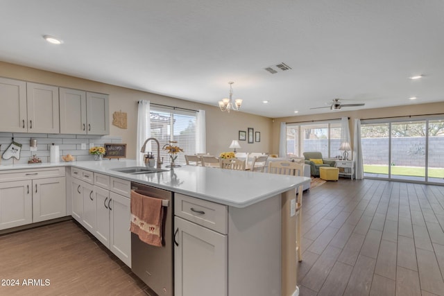 kitchen with dark wood-type flooring, a wealth of natural light, stainless steel dishwasher, and decorative light fixtures