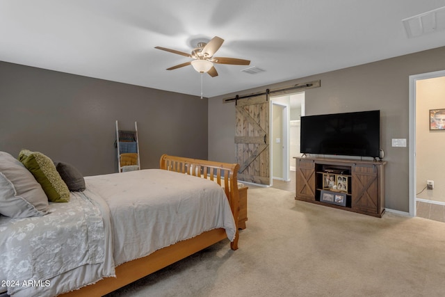 bedroom featuring ensuite bathroom, a barn door, carpet flooring, and ceiling fan