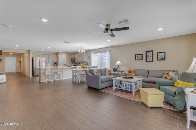 living room featuring ceiling fan with notable chandelier and hardwood / wood-style floors