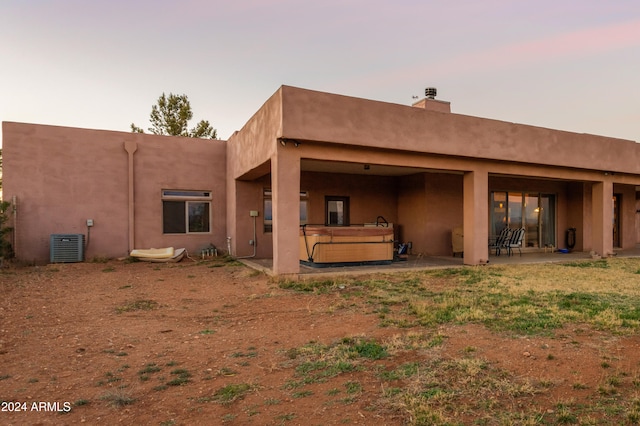 back house at dusk with a patio area and a hot tub