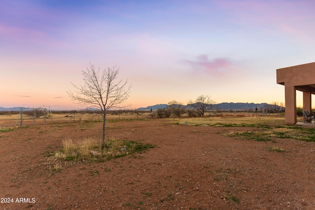 yard at dusk with a mountain view and a rural view