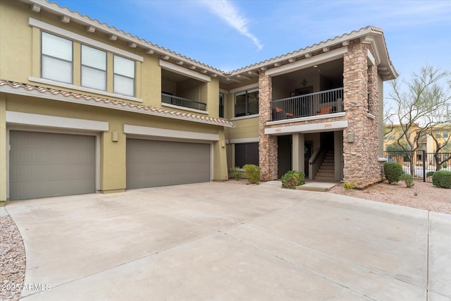 townhome / multi-family property featuring fence, stairs, stucco siding, driveway, and an attached garage