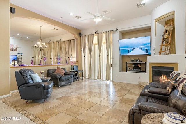 8167 E Sand Flower Dr, Scottsdale, AZ 85266 - living area with arched walkways, ceiling fan, light tile patterned floors, a glass covered fireplace, and baseboards