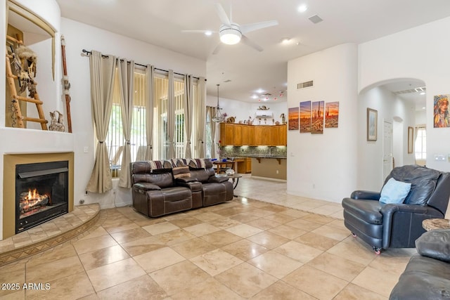 8167 E Sand Flower Dr, Scottsdale, AZ 85266 - living room with ceiling fan, arched walkways, light tile patterned floors, and a fireplace