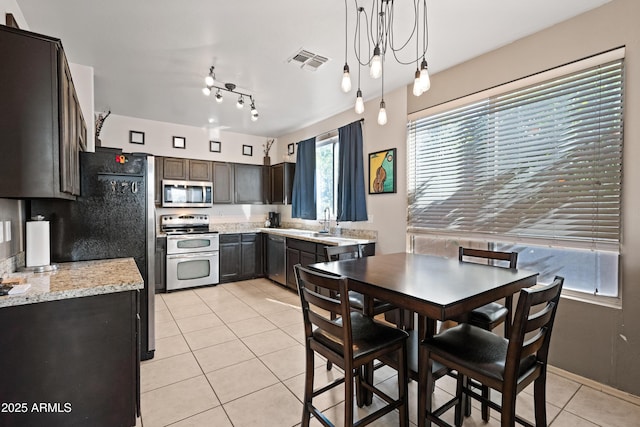 kitchen featuring light tile patterned flooring, stainless steel appliances, a healthy amount of sunlight, and decorative light fixtures