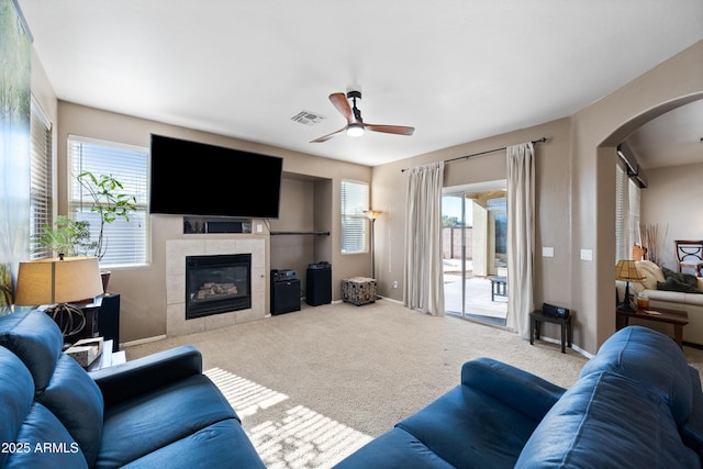 carpeted living room featuring ceiling fan and a tile fireplace