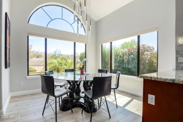 dining area featuring high vaulted ceiling and light wood-type flooring