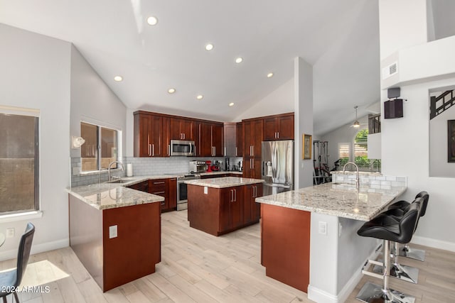 kitchen featuring appliances with stainless steel finishes, light stone counters, kitchen peninsula, backsplash, and a center island