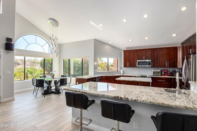 kitchen featuring stainless steel appliances, backsplash, sink, and light stone countertops