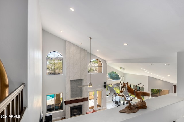 living room with a healthy amount of sunlight, ceiling fan, high vaulted ceiling, and a high end fireplace