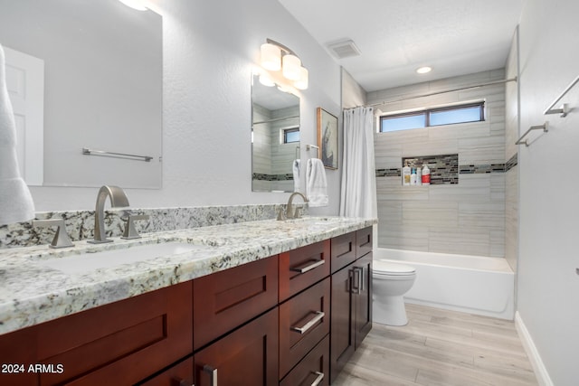 full bathroom featuring toilet, double sink vanity, hardwood / wood-style floors, and shower / bath combo