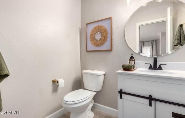 half bathroom with toilet, vanity, and baseboards