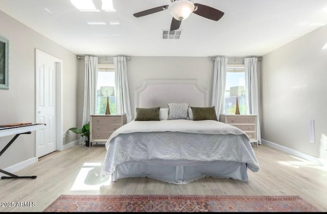 bedroom featuring visible vents, multiple windows, light wood-style floors, and baseboards