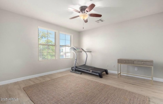 exercise area featuring ceiling fan, visible vents, baseboards, and wood finished floors