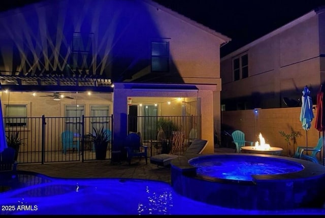 exterior space featuring a pool with connected hot tub, a water slide, fence, an outdoor fire pit, and a patio