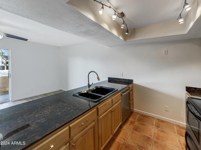 kitchen featuring sink, stainless steel dishwasher, dark stone counters, ceiling fan, and a textured ceiling