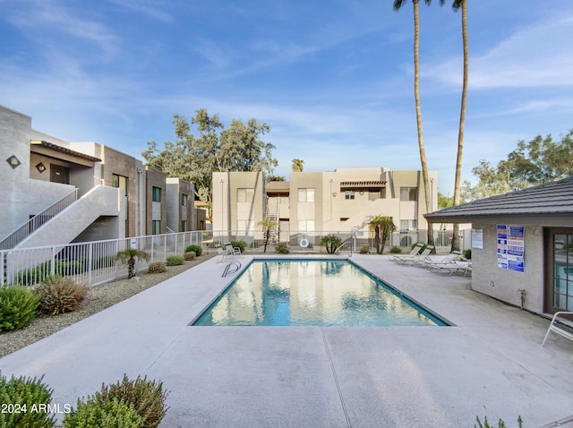 community pool with a residential view, fence, and a patio