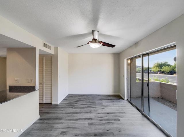 spare room with visible vents, a ceiling fan, a textured ceiling, wood finished floors, and baseboards