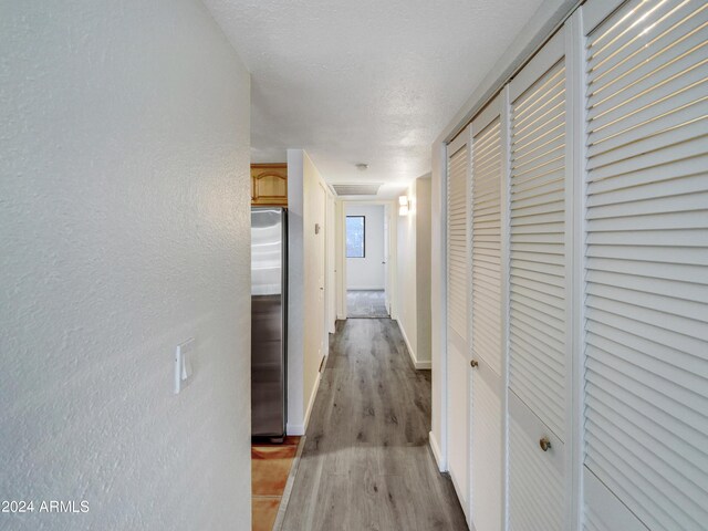 corridor featuring a textured ceiling and hardwood / wood-style floors