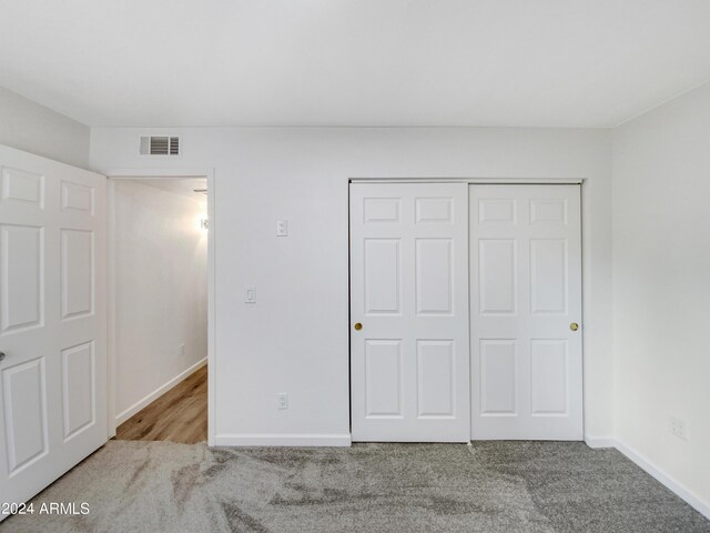 unfurnished bedroom featuring a closet and light carpet