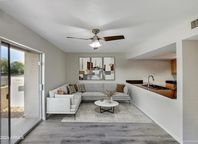 living room featuring ceiling fan, hardwood / wood-style flooring, and sink