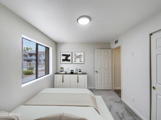 bedroom with visible vents, light carpet, and baseboards