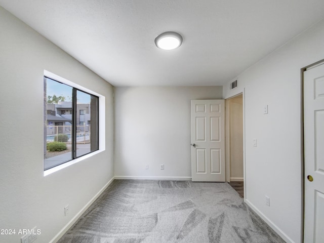 spare room featuring carpet floors, visible vents, and baseboards