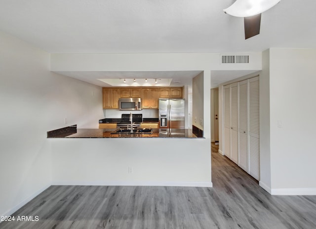 kitchen with stainless steel appliances, visible vents, a sink, wood finished floors, and a peninsula