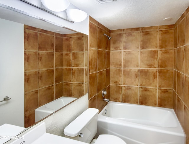 bathroom with a textured ceiling, shower / bath combination, and toilet