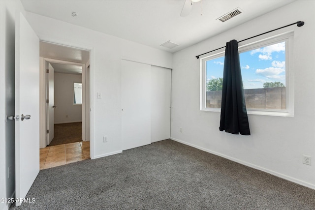 unfurnished bedroom featuring carpet, a closet, baseboards, and ceiling fan