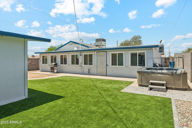 back of property with a hot tub and a patio area