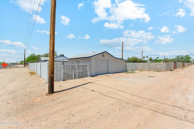 view of outbuilding with fence, an outbuilding, and dirt driveway